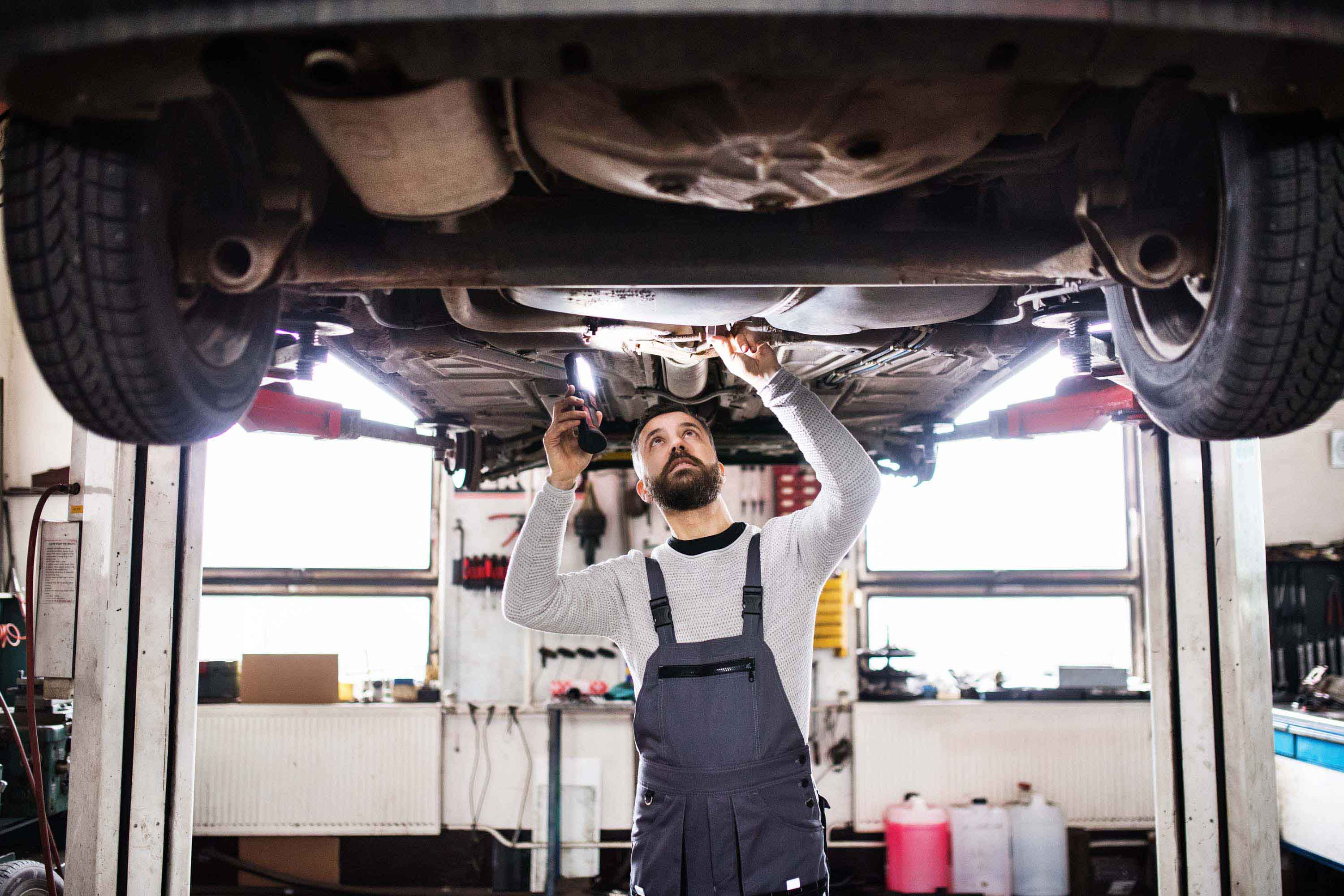 man inspects under car