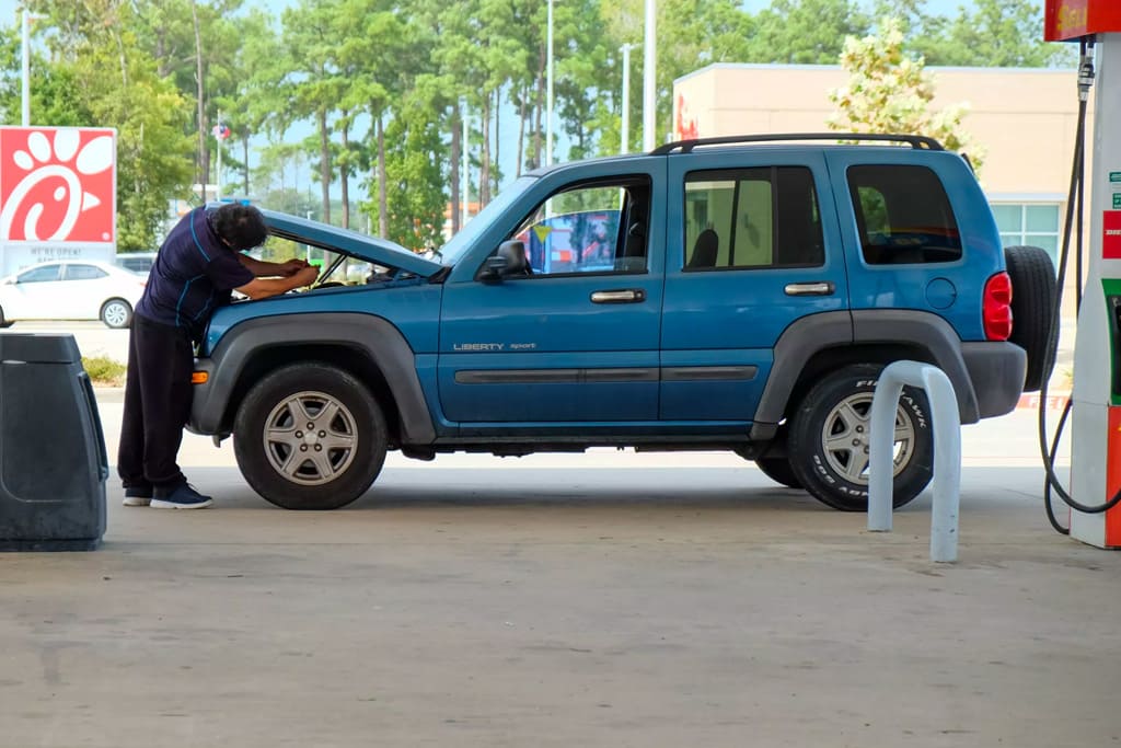 old mechanic in blue attire performs inspection on car