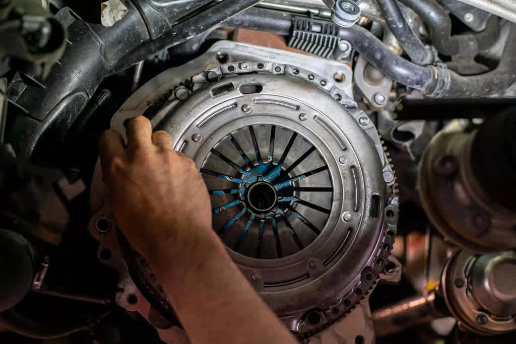 old mechanic in blue attire performs inspection on car