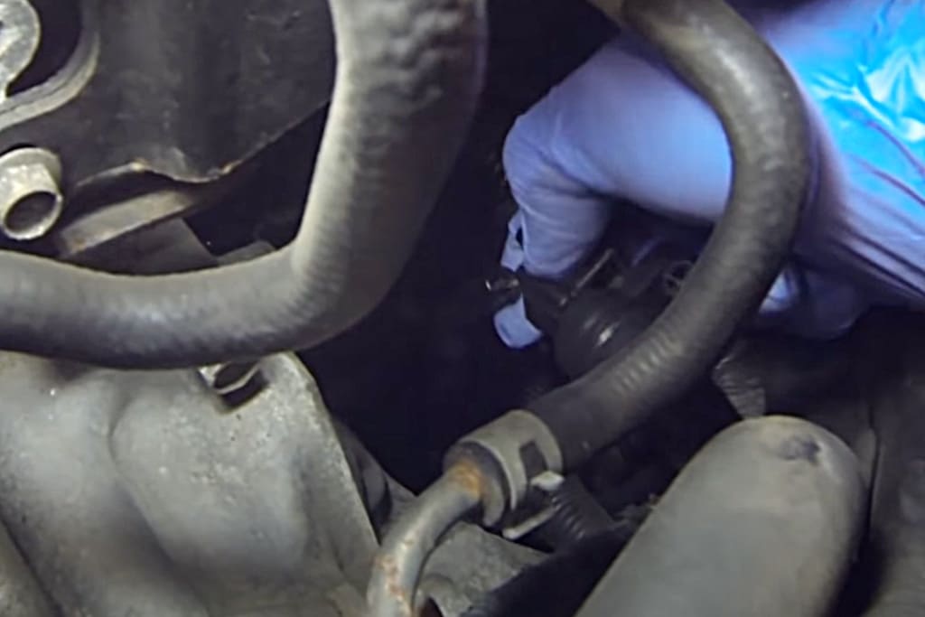 old mechanic in blue attire performs inspection on car