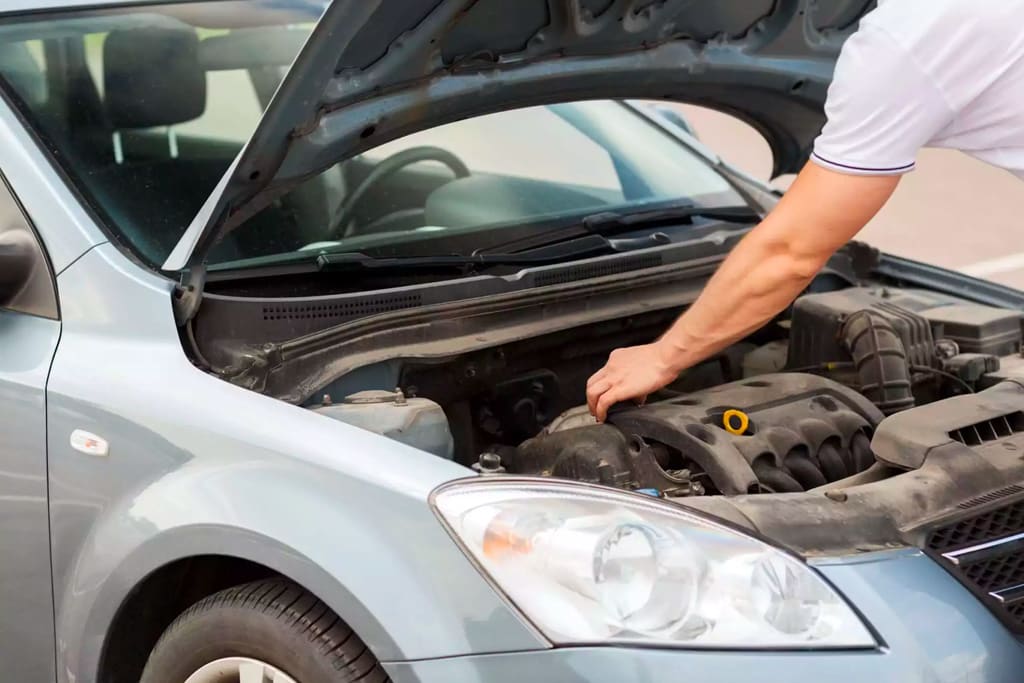 old mechanic in blue attire performs inspection on car