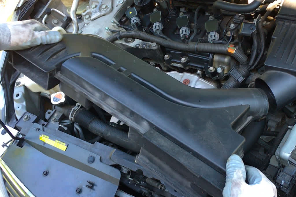 old mechanic in blue attire performs inspection on car