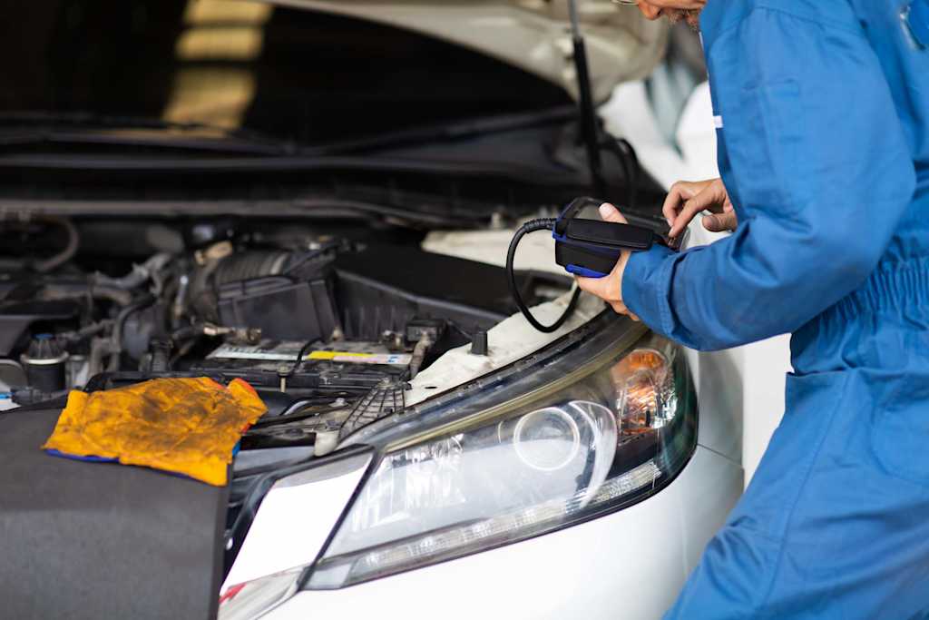 old mechanic in blue attire performs inspection on car